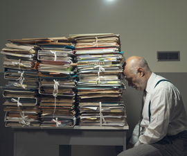 Depressed man in front of stacks of folders