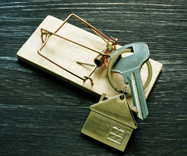 Key attached to house shaped keychain laying on wood moustrap