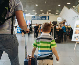 Father and young boy in airport with backpack and suitcase. Travelling with kids 