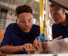 Young teenager being taught how to cut steel from older man